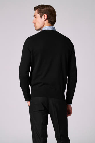 Pull noir à col rond de Bruce & Butler, vu par derrière, avec un chemisier en dessous et des pantalons noirs.
