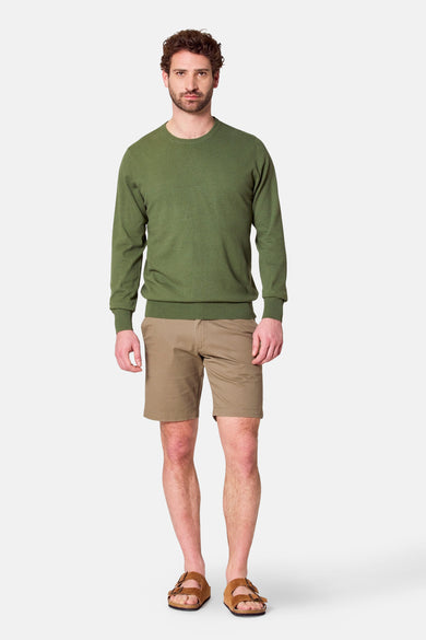 T-shirt vert avec col rond de Bruce & Butler, porté avec des shorts kaki et des sandales.