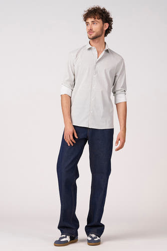 Chemise blanche à manches longues de Bruce & Butler, avec motif fin, portée avec un jean foncé et des baskets.