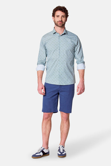 Groen overhemd met lange mouwen van Bruce & Butler, met fijn bladmotief, gedragen met blauwe shorts en sneakers.
