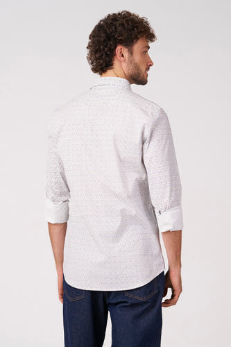 Chemise blanche à manches longues de Bruce & Butler, avec un motif fin et des manches retroussées, combinée avec un jean foncé.
