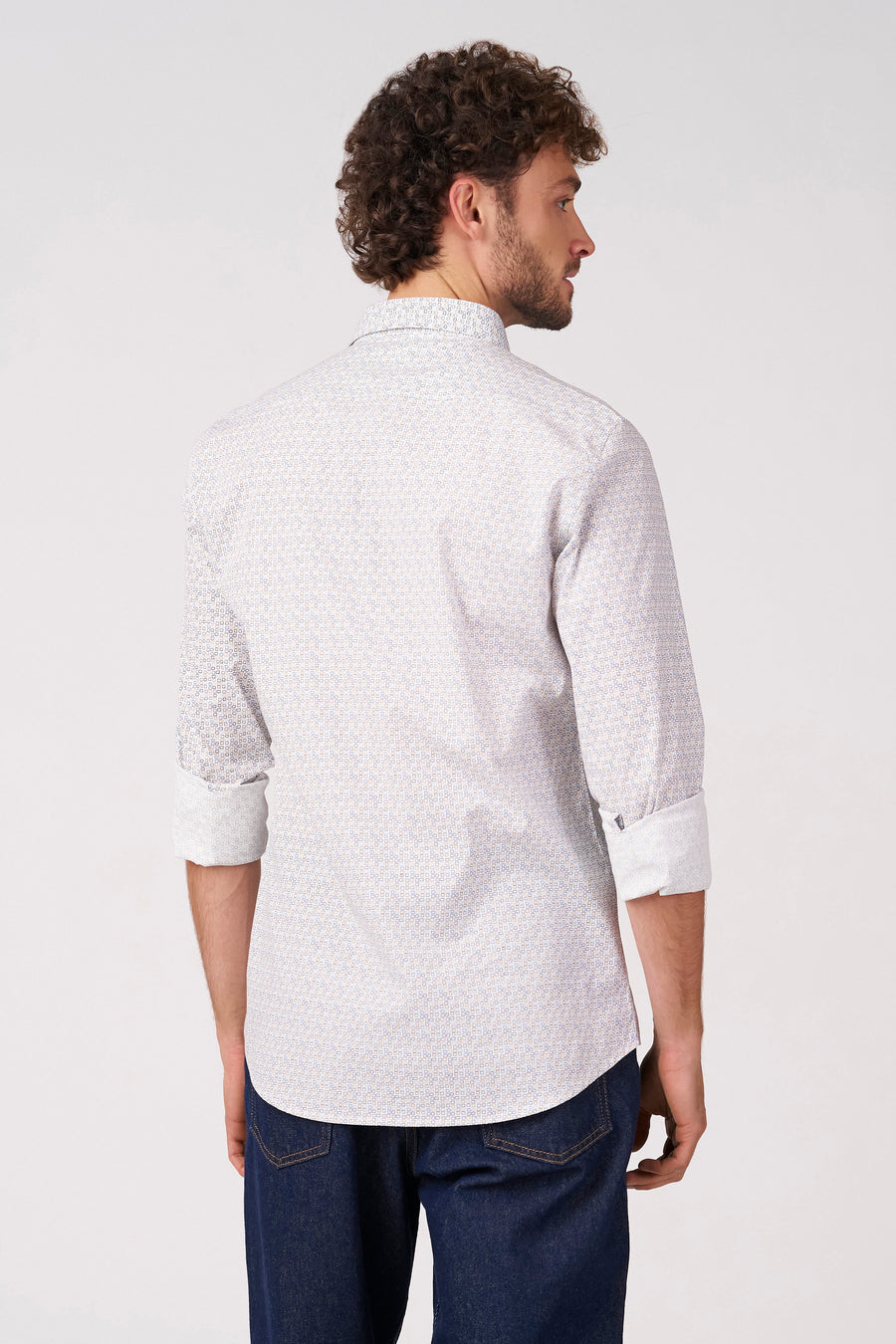 Chemise blanche à manches longues de Bruce & Butler, avec un motif fin et des manches retroussées, combinée avec un jean foncé.