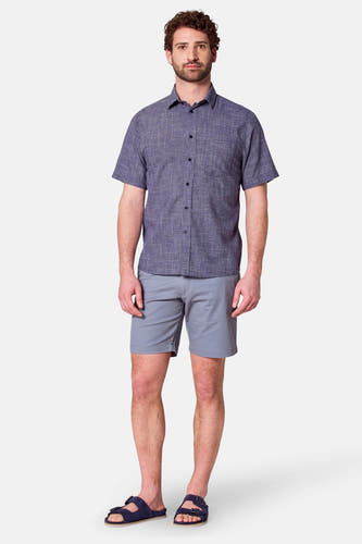 Chemise bleue à manches courtes de Bruce & Butler, avec un motif de rayures subtil, associée à des short gris et des sandales.
