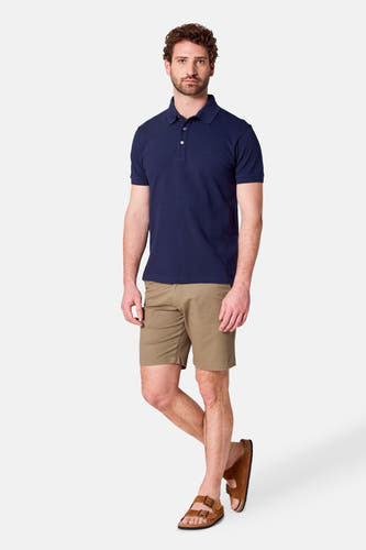 Polo bleu marine à manches courtes de Bruce & Butler, porté avec des shorts kaki et des sandales brunes.