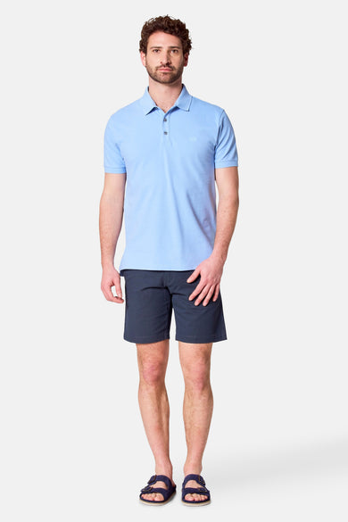 Man in blauw poloshirt en donkerblauwe shorts.