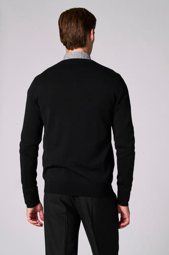 Veste V-halstrui Bruce & Butler, vue en, avec un une-shirt imprimé dessous et un pantalon noir.