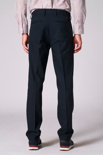Pantalon de costume bleu Bruce & Butler, avec un design simple et des poches arrière, porté avec une chemise à motif rouge.