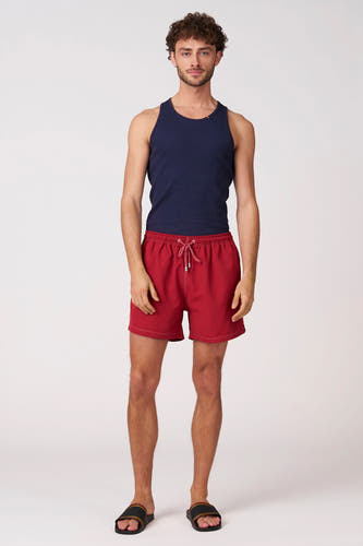 Short de bain rouge de Bruce & Butler avec cordon de serrage et coutures blanches, porté par un homme.