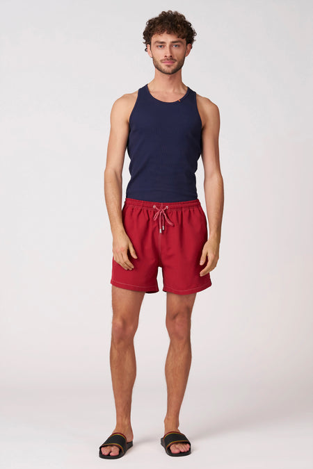 Short de bain rouge de Bruce & Butler avec cordon de serrage et coutures blanches, porté par un homme.