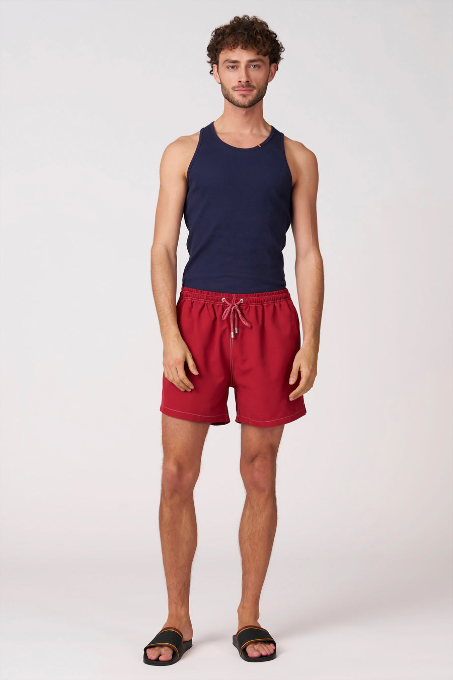 Short de bain rouge de Bruce & Butler avec cordon de serrage et coutures blanches, porté par un homme.