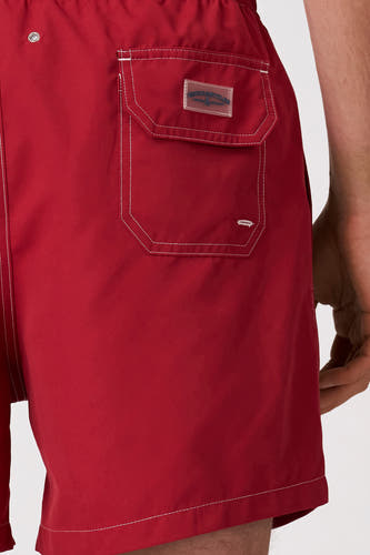 Short de bain rouge de Bruce & Butler avec surpiqûres contrastées blanches, une poche arrière avec écusson logo transparent et un œillet argenté.