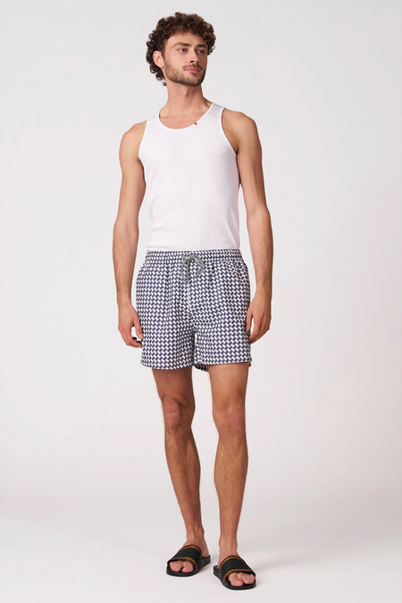 Short de bain multicolore de Bruce & Butler avec motif à carreaux fin et cordon de serrage, porté par un homme avec un débardeur blanc et des sandales noires.