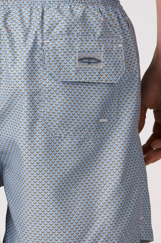Short de bain bleu de Bruce & Butler avec un motif fin de formes en V marron et orange et une poche arrière avec une étiquette de marque transparente.