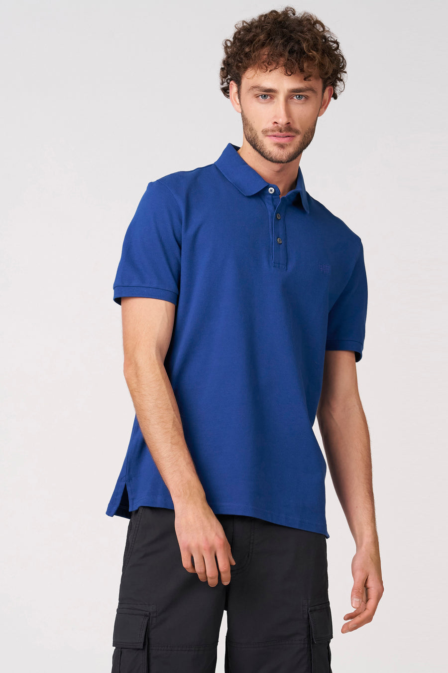 Polo bleu à manches courtes de Bruce & Butler, vue de dos, portée avec un pantalon noir.