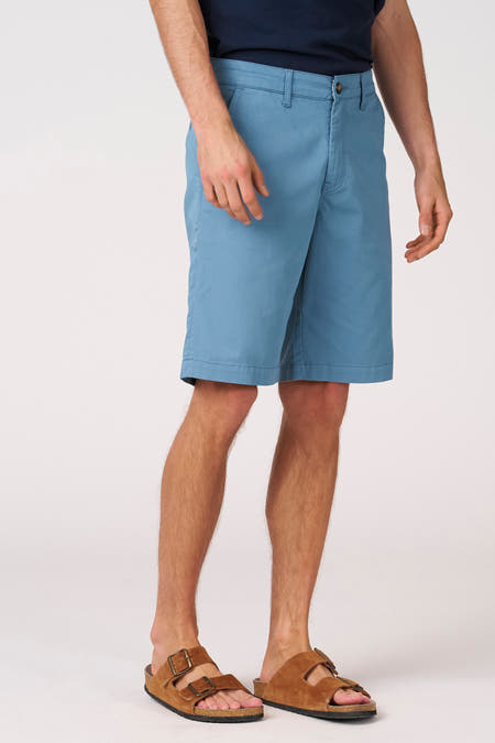 Short bleu de Bruce & Butler, avec poche latérale et porté avec des sandales marron.