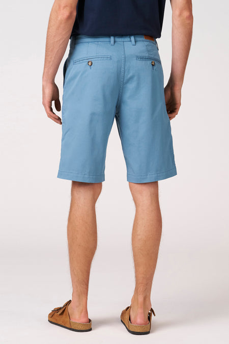 Short bleu de Bruce & Butler, vue de dos, avec boutons en bois et mules en cuir marron.