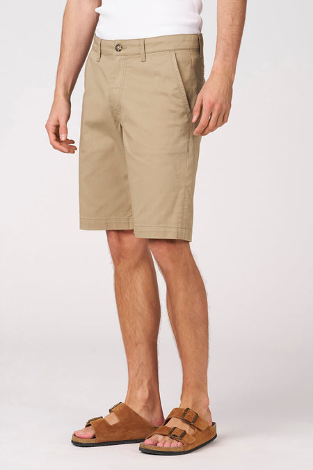 Short beige de Bruce & Butler, porté avec des sandales marron et un t-shirt blanc, en vue latérale.