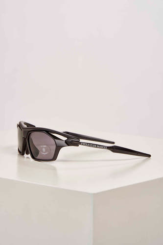 Lunettes de soleil noires de Cyclo Club Marcel, posées sur une surface blanche, vue de face.