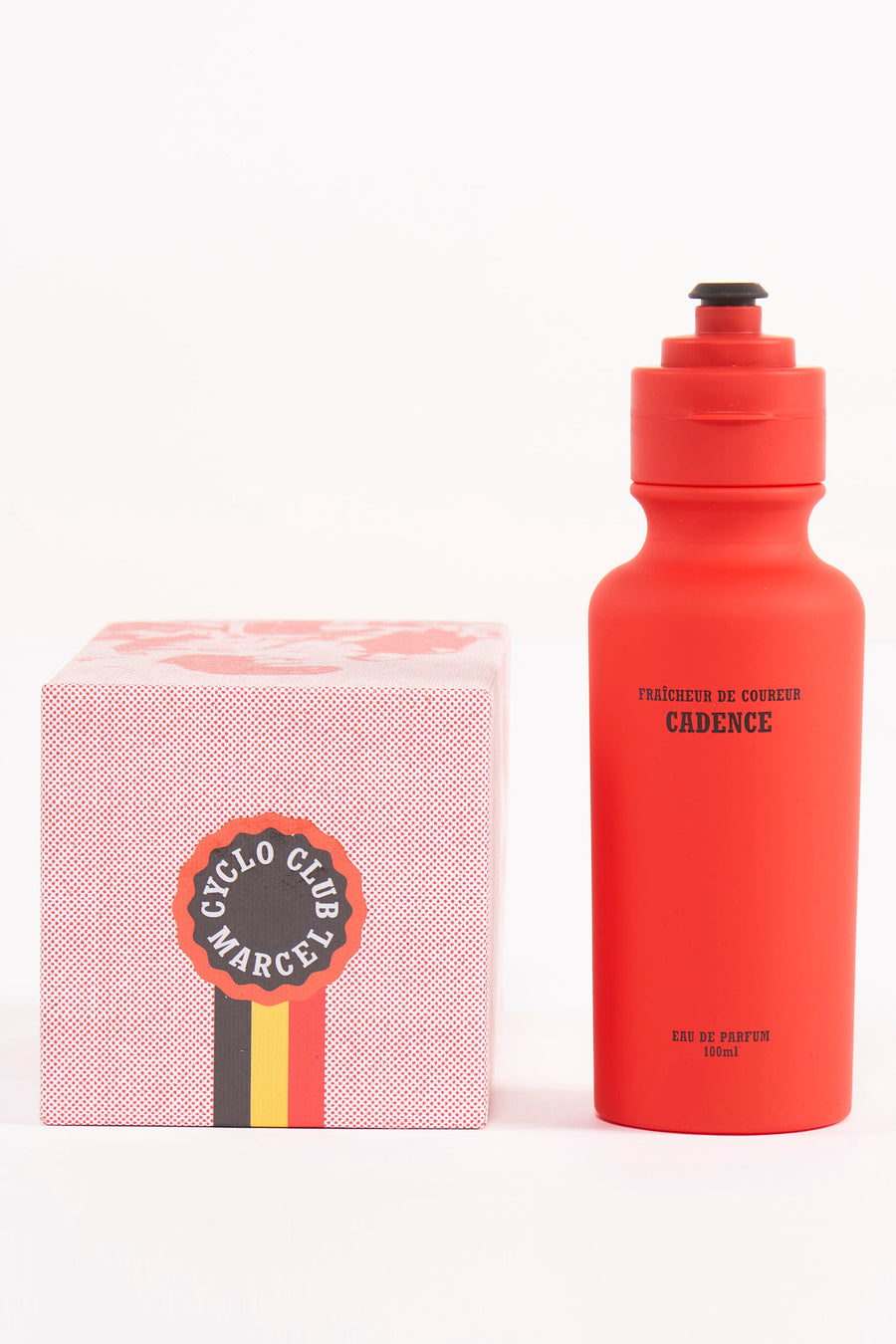 Bouteille de parfum rouge de Cyclo Club Marcel, posée à côté d'une boîte en carton avec un motif de points rouges et un logo.