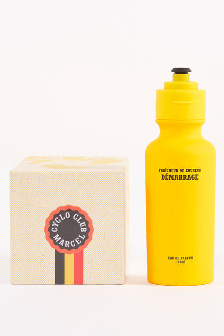 Parfum jaune de Cyclo Club Marcel, sous forme d'un bidon avec un bouchon noir, à côté d'une boîte.