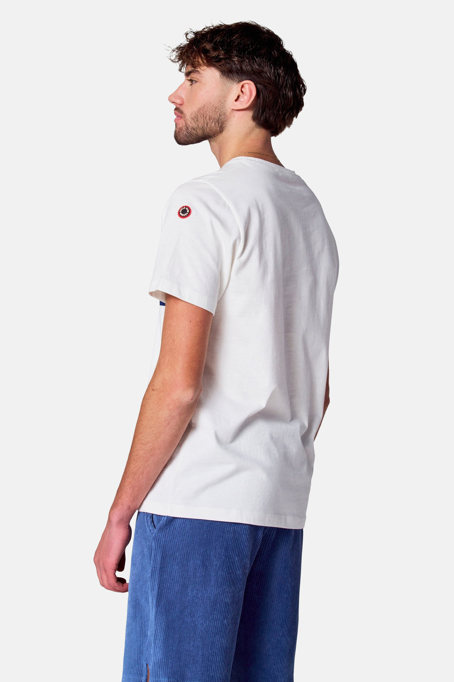Wit T-shirt met korte mouwen van Cyclo Club Marcel, met logo op de mouw, gecombineerd met blauwe corduroy shorts.