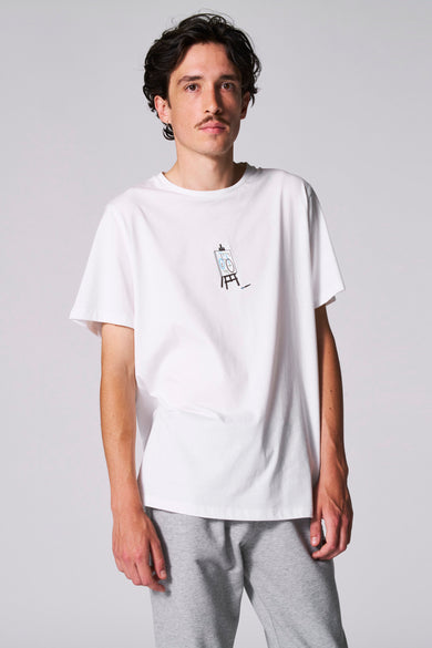 T-shirt blanc à manches courtes de Cyclo Club Marcel, avec un logo sur la manche, associé à un pantalon de jogging gris.