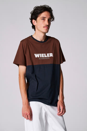 Blauw T-shirt met korte mouwen van Cyclo Club Marcel, met bruin bovenstuk en witte broek.
