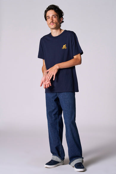 T-shirt bleu à manches courtes de Cyclo Club Marcel, avec un petit imprimé et associé à des jeans et des baskets.