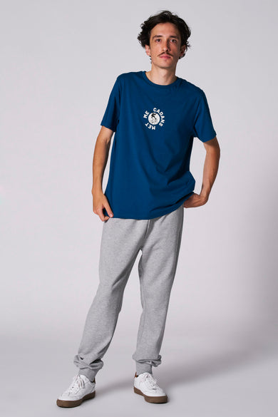 T-shirt bleu à manches courtes de Cyclo Club Marcel, avec une impression blanche, associé à un short de jogging gris et des baskets blanches.