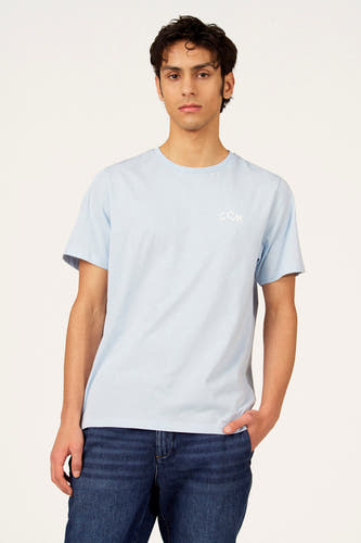 T-shirt bleu à manches courtes de Cyclo Club Marcel, avec imprimé blanc au dos, combiné avec un jean foncé.