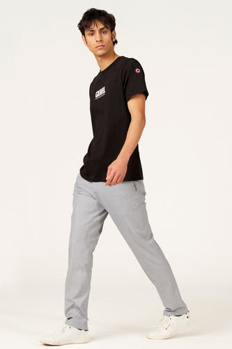 T-shirt à manches courtes noir de Cyclo Club Marcel, avec imprimé blanc et porté avec un pantalon gris et des baskets blanches.