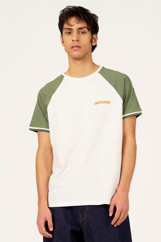 T-shirt blanc à manches courtes Cyclo Club Marcel, avec manches raglan vert olive contrastantes et un jean.