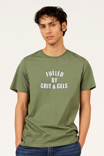T-shirt vert à manches courtes de Cyclo Club Marcel, avec petit logo sur la manche, combiné avec un jean foncé.