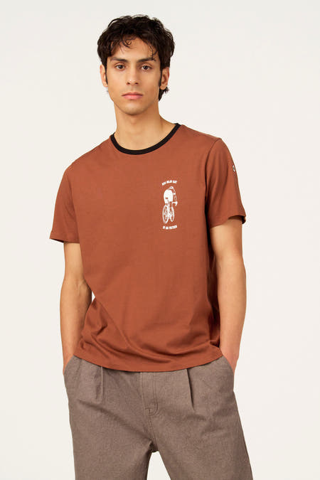Beige T-shirt met korte mouwen van Cyclo Club Marcel, met een print aan de voorkant en gedragen met een bruine pantalon.
