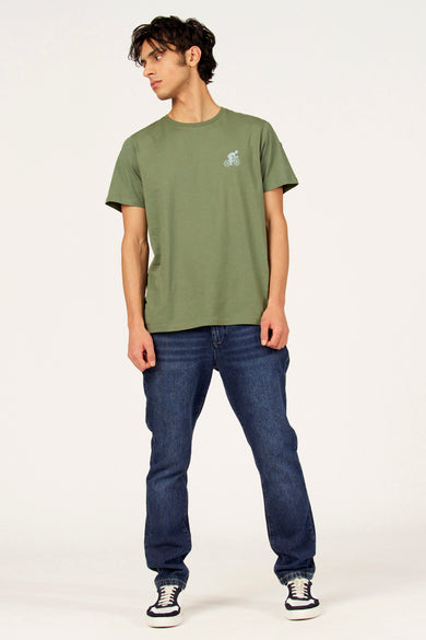 T-shirt vert à manches courtes de Cyclo Club Marcel, avec petit motif de vélo et combiné avec un jean foncé et des baskets.