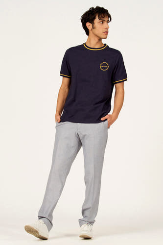 T-shirt bleu à manches courtes de Cyclo Club Marcel, fini avec des accents jaunes et un logo, combiné avec un pantalon gris et des baskets blanches.