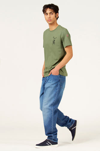 T-shirt vert à manches courtes de Cyclo Club Marcel, avec un imprimé de cycliste, porté avec un jean et des baskets bleu foncé.
