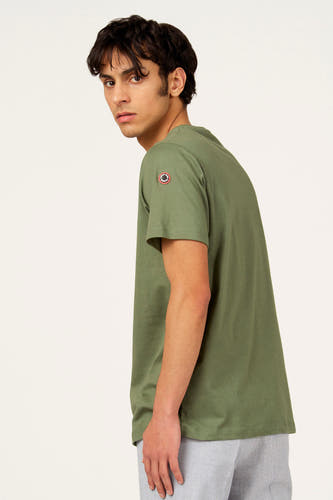 Groen T-shirt met korte mouwen van Cyclo Club Marcel, met een logo-patch op de mouw, gedragen met een gestreepte broek.
