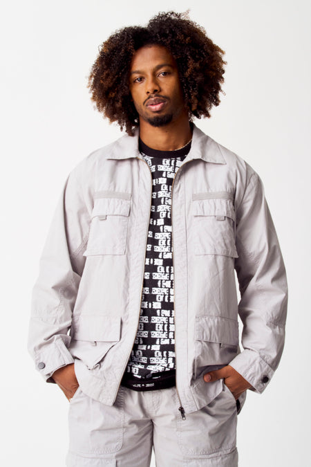 Manteau court gris de COELY, avec des poches brodées et un T-shirt noir avec une impression blanche en dessous.