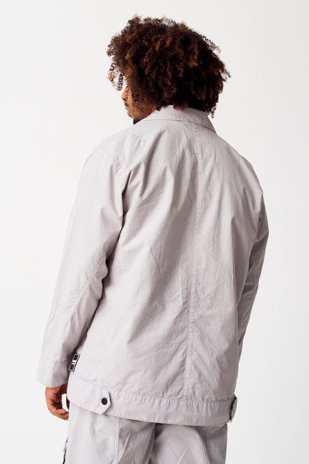Manteau court gris de COELY, vu de dos avec des cheveux foncés bouclés et un pantalon gris.