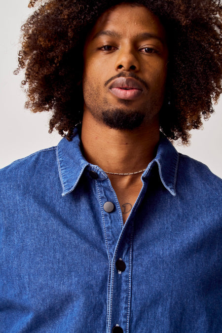 Chemise en jeans bleue de COELY, avec des boutons noirs et une chaîne argentée.