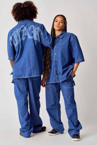 Chemise en jeans bleue de COELY, à manches courtes et col boutonné, associée à un pantalon en jeans coordonné.