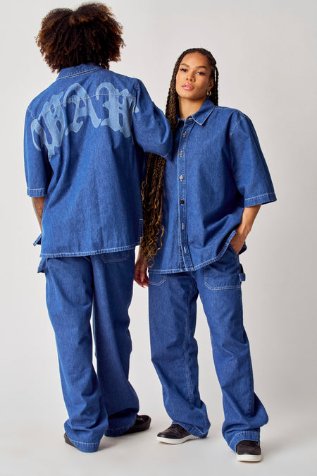 Chemise en jeans bleue de COELY, à manches courtes et col boutonné, associée à un pantalon en jeans coordonné.