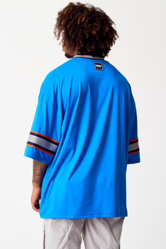 T-shirt bleu de COELY, avec des manches rayées et un étiquette dans le cou.