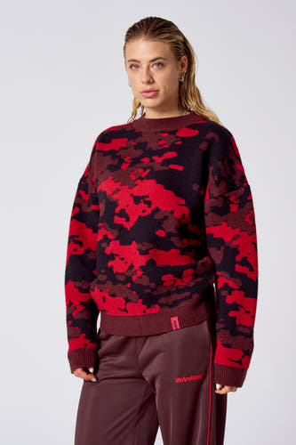 T-shirt rouge avec col rond de COELY, à un motif camouflage rouge et noir, associé à un pantalon de jogging marron.