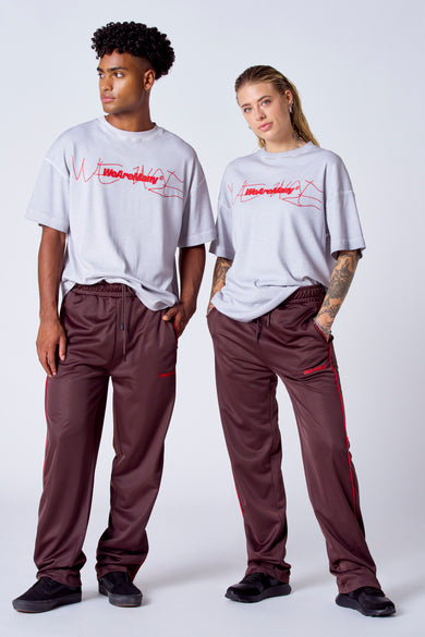 T-shirt gris à manches courtes de COELY, avec une impression rouge, porté avec un short d'entraînement marron et des rayures rouges.
