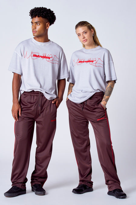 T-shirt gris à manches courtes de COELY, avec une impression rouge, porté avec un short d'entraînement marron et des rayures rouges.