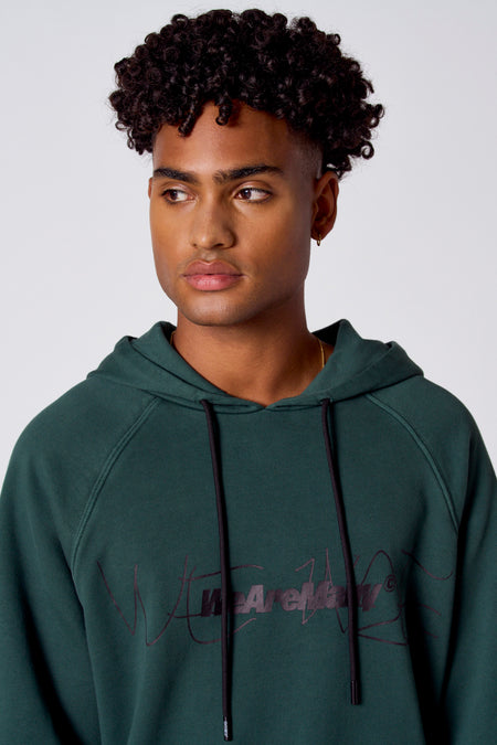 Sweat-shirt vert avec capuche de COELY, avec des cordons noirs et un texte détaillé sur l'avant.