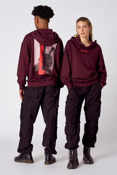 Pull bordeaux avec capuche de COELY, imprimé sur le dos et associé à un pantalon cargo noir et des bottes noires.