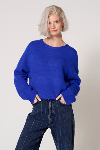 T-shirt bleu avec col rond de Clouds of Fashion, porté avec un jean à rayures verticales.